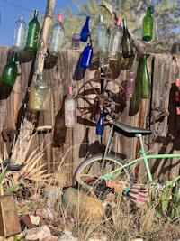 a bicycle is parked next to a fence full of bottles